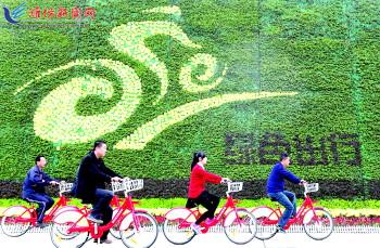 市民騎公共自行車路過市人民廣場(chǎng)一處花壇。記者 張馳